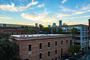 A red brick building with a white roof is in the foreground with a city skyline in the background.