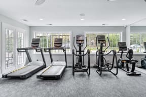 a gym with cardio machines and windows in a building