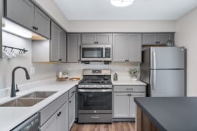 an empty kitchen with stainless steel appliances and white cabinets