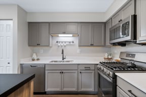an empty kitchen with stainless steel appliances and gray cabinets