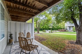 a backyard patio with a table and chairs and a tree
