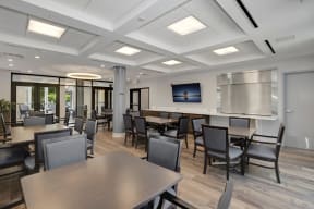a common room with tables and chairs and a television on the wall