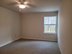 an empty room with a ceiling fan and a window