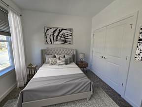 A bedroom with a large bed and a painting on the wall.
