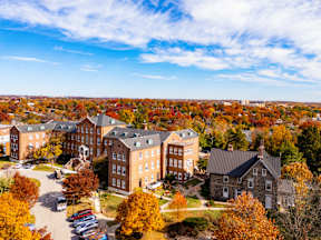 A large building complex surrounded by trees with autumn leaves.