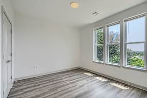 A room with a white door, a window, and a wooden floor.