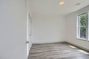 A room with a wooden floor and a window on the right side.