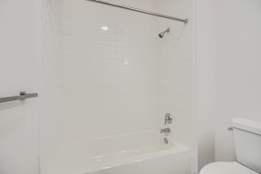 A white bathroom with a tub and toilet.