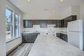 A kitchen with a white fridge and black cabinets.