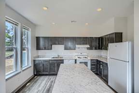 A kitchen with black cabinets and a white refrigerator.
