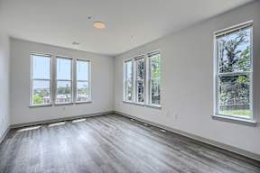 A large empty room with wooden floors and windows.
