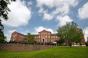 A large red brick building with a green lawn in front.