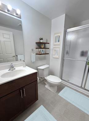 A bathroom with a toilet, sink, and mirror.
