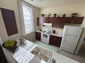 A kitchen with a white fridge and a bowl of apples on the counter.