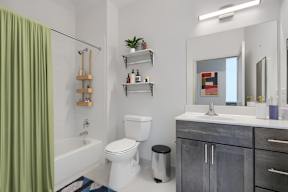 A bathroom with a white toilet, a white sink, and a green shower curtain.