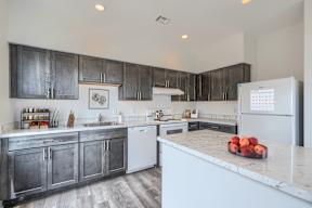 A kitchen with a white fridge and a marble counter top.