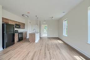 A kitchen with a black fridge and wooden floors.
