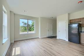 A spacious room with wooden flooring and a large window.