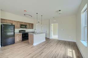 A kitchen with wooden floors and a black refrigerator.