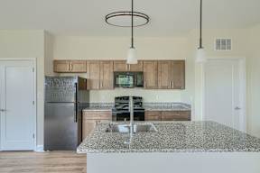 A kitchen with a granite countertop and a refrigerator.