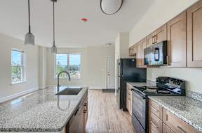A kitchen with granite countertops and a black refrigerator.