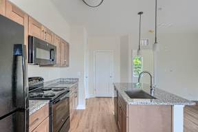 A kitchen with a black refrigerator, a black stove, and a black microwave.