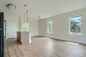A spacious living room with a kitchenette and hardwood floors.