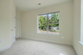 A room with a large window and carpeted floor.