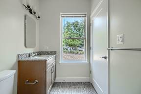 A bathroom with a window that shows a backyard.