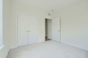 A room with white walls and carpeted floor with three doors.