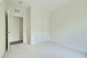 A room with a white door, a white closet, and a white carpet.
