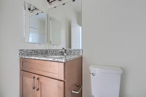 A bathroom with a toilet, sink, and mirrors.