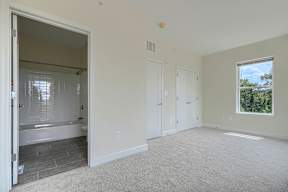 A large empty room with a bathtub and a window.