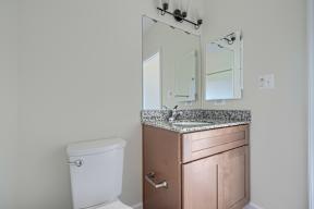 A bathroom with a toilet, sink, and mirror.