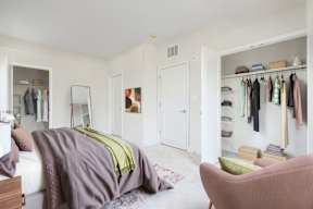A bedroom with a bed, chair, and closet.