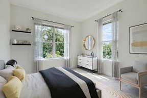 A bedroom with a large bed, a dresser, a chair, and a window with curtains.
