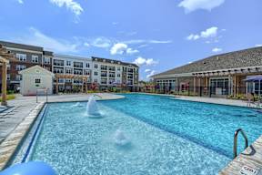 A large outdoor swimming pool with a fountain in the middle.
