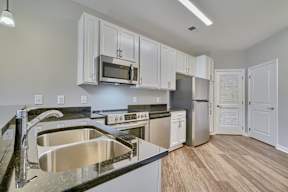 A kitchen with a stainless steel sink and white cabinets.