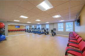A gym with exercise equipment and red chairs.