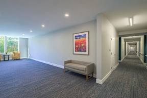 A hallway with a bench and a painting on the wall.