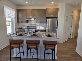 A kitchen with a stainless steel refrigerator, oven, and bar stools.