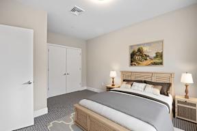 A bedroom with a bed, nightstands, and a painting on the wall.