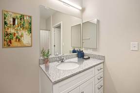 A bathroom with a sink, mirror, and a painting on the wall.