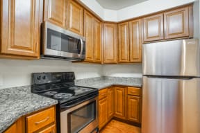an empty kitchen with wood cabinets and stainless steel appliances