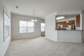 an empty living room with a kitchen in the corner