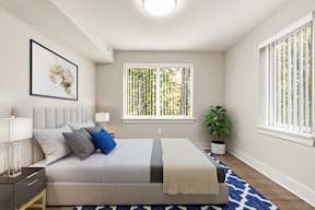 A bedroom with a bed, nightstand, and a plant.