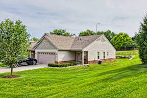 A house with a garage and a tree in front of it.