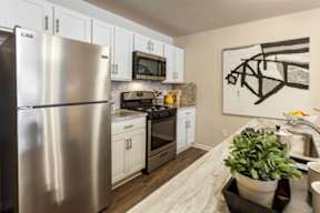A modern kitchen with a stainless steel refrigerator and white cabinets.