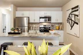 A kitchen with a stainless steel refrigerator, microwave, and oven.