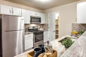 A kitchen with a refrigerator, oven, and microwave.